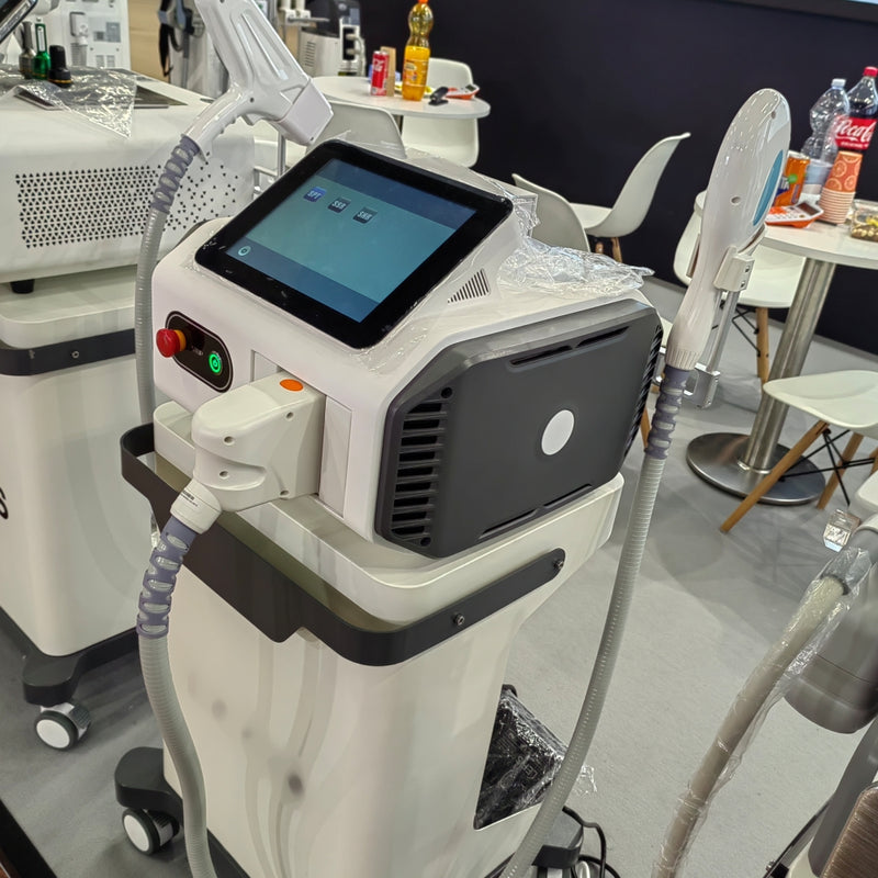 Baltas IPL plaukų šalinimo aparatas su mėlynu liečiamuoju ekranu ir pilka rankena, pastatytas ant balto fono