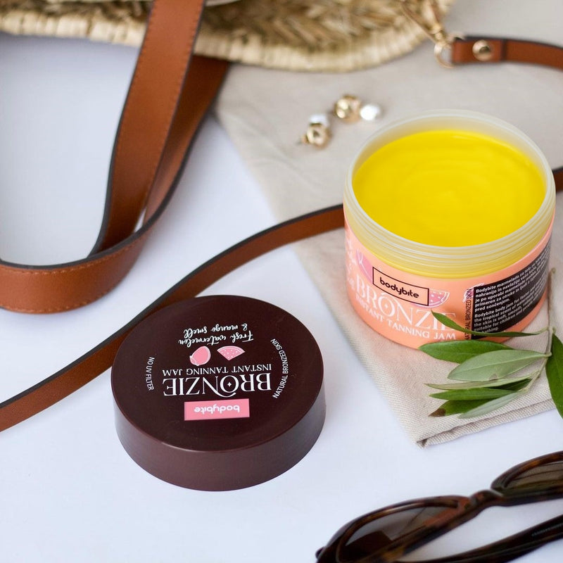 Bodybite BRONZIE Instant Tanning Jam with Watermelon and Mango in a yellow jar next to a stylish handbag